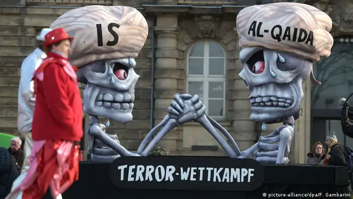 Terror-Wettkampf auf einem Düsseldorfer Motivwagen beim Rosenmontagszug: Zwei Sklette, die jeweils eine Mütze mit der Aufschrift IS und Al Kaida tragen, messen ihre Kräfte beim Armdrücken, Foto von Federico Gambarini/dpa
