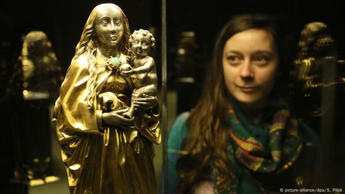 A museum visitor looks at a golden Mary and Jesus statue that is part of the Guelph Treasure