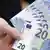 A hand fans out a wad of freshly-printed 20 euro banknotes