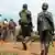 Congo soldier walk past UN peacekeepers