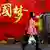 北京市的一位女性居民走過一面印有「中國夢」的宣傳大字海報
