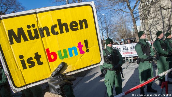 Plakat 'München ist bunt' vor Polizisten und Demonstranten mit dem Plakat 'Die Rechte' (Foto: Peter Kneffel/dpa)