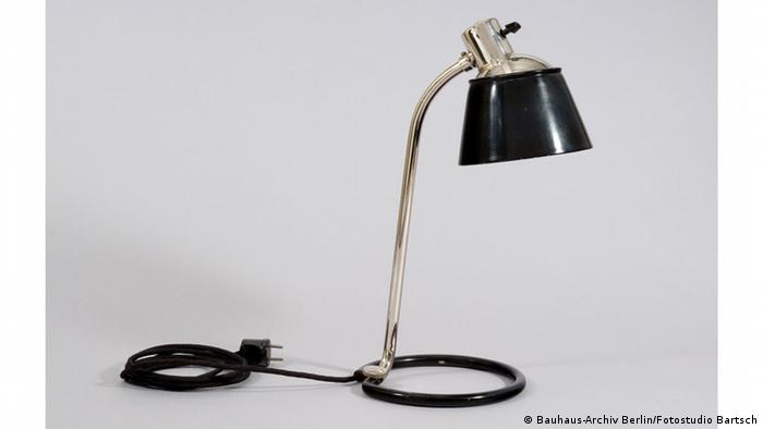 Знаменита лампа Ваґенфельда була першою, спроектованою Баугаузом, а ця лампа Борманна 1932 року - останньою. Її було створено у слюсарній майстерні Баугаузу в Дессау і виготовлено на заводі. Особливості лампи: кабель, схований в металеву трубку, яка слугує підставкою, а також нещільно прикріплений абажур, щоб коригувати яскравість світла.