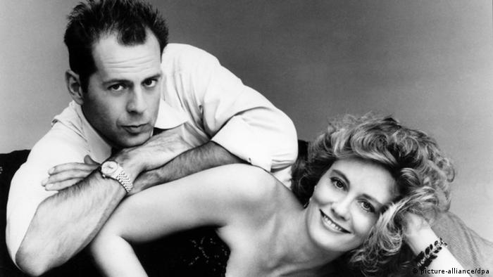 Bruce Willis & Cybill Shepherd, man leans on smiling woman who is lying on her side