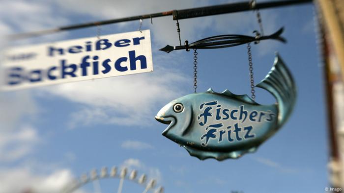 An einem Restaurant hängt ein Schild mit der Aufschrift Heißer Backfisch neben einem Fisch