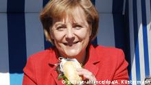 Bundeskanzlerin Angela Merkel (CDU) sitzt am Samstag (02.05.2009) mit einem Heringsbrötchen im Restaurant Moby Dick im Sassnitzer Hafen. Die Kanzlerin hat als Bundestagsabgeordnete ihren Wahlkreis auf Rügen. In Nordvorpommern wird gern Fisch gegessen und in Sassnitz wird er täglich frisch angelandet. Der frühere Steigenberger-Spitzenkoch Holger Nebel hat in seinem Restaurant Moby Dick eine ganz besondere Art, Matjes mit Kräutern oder Bismarckhering im warmen Brötchen zuzubereiten. Foto: Andreas Küstermann dpa/lmv +++(c) dpa - Bildfunk+++