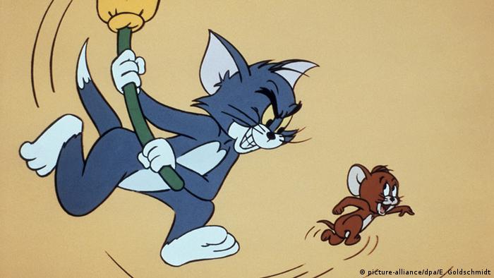 Filmstill aus dem Animationsfilm Tom und Jerry. Zu sehen ist der blau-graue Kater Tom mit einem Besen in der Hand, vor ihm läuft vergnügt die braune Maus Jerry (Foto: picture-alliance/dpa/E. Goldschmidt).