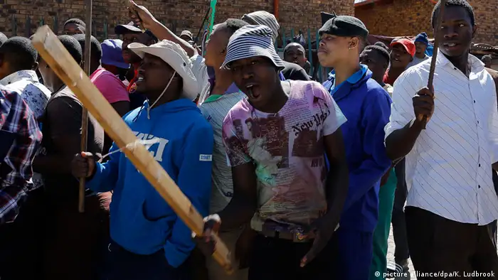 Local South African men carry clubs as they call for foreign shop owners to leave the area during a wave of xenophobic violence 