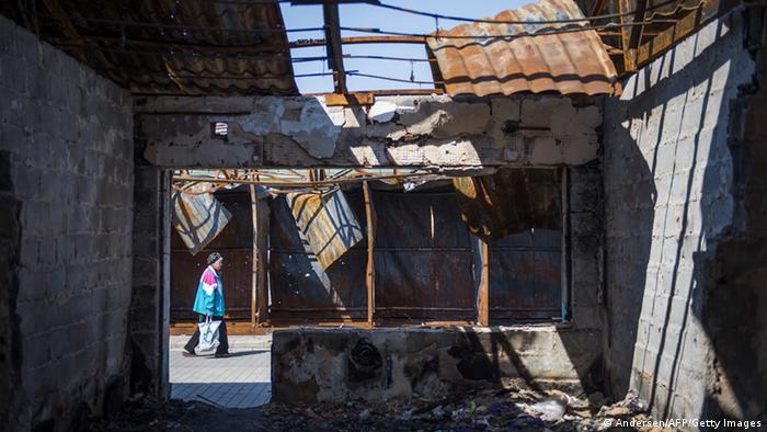 A woman carries her shopping past a burnt out market stall near the main station in April 2015 in Donetsk in eastern Ukraine.