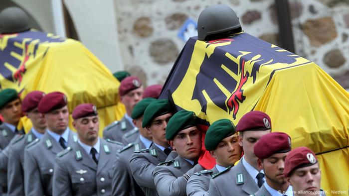 Bundeswher soldiers carry the insignia-wrapped coffins of their fallen comrades