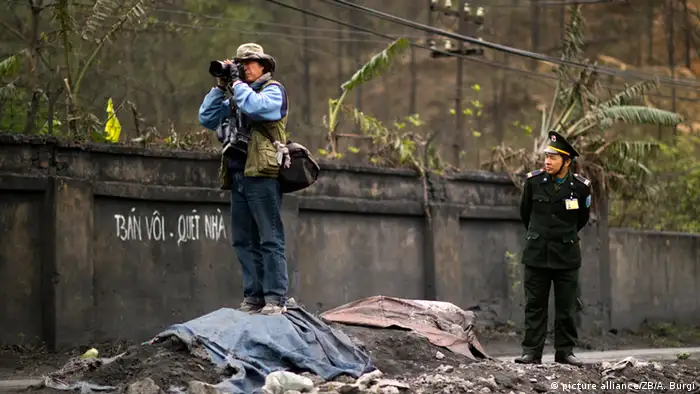 Ein Pressefotograf steht auf einem Schuttberg. Ein vietnamesischer Soldat beobachtet ihn. (Foto: picture alliance/ZB/A. Burgi)