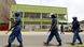 Three Policemen in riot gear walk outside broadcasting building