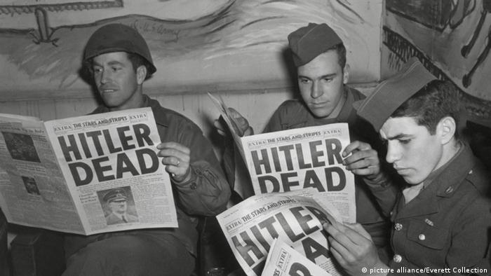 Soldiers reading newspapers with Hitler Dead headline (Foto: picture alliance/Everett Collection)