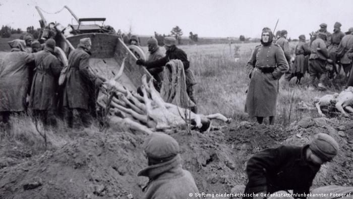 Von einem Karren werden die nackten Leichen in ein Grab gekippt - Foto: Stiftung niedersächsische Gedenkstätten