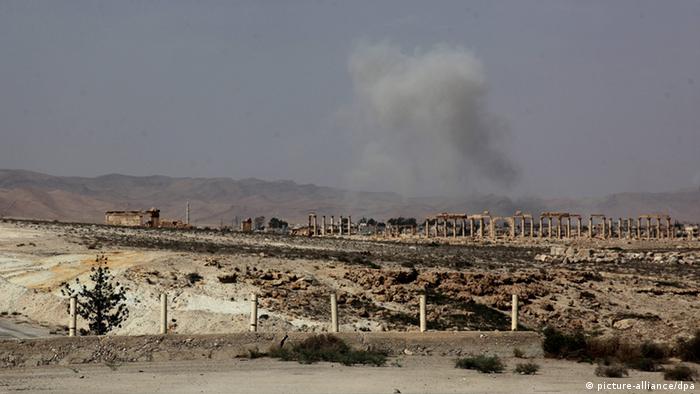 Античные руины Пальмиры со столбом дыма над ними