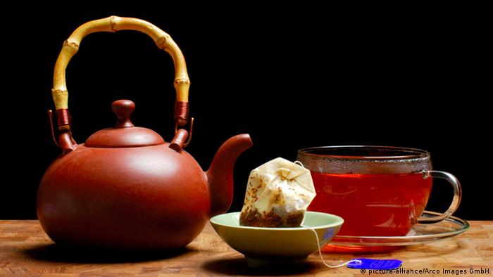 A teapot next to a tea cup holding rooibos tea