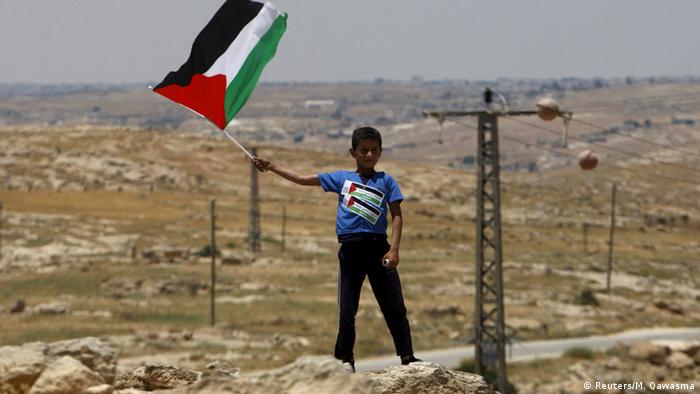 Ein Kind hält die palästinänsische Fahne hoch in der Westbank Susya