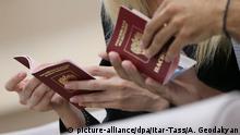 ITAR-TASS: MOSCOW, RUSSIA. AUGUST 27, 2013. Visitors checking their passports for Schengen visa at visa application centre of Germany. (Phot ITAR-TASS / Artyom Geodakyan)