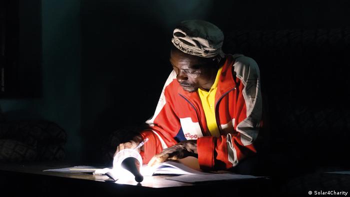 A man reads a book that is illuminated by a small light