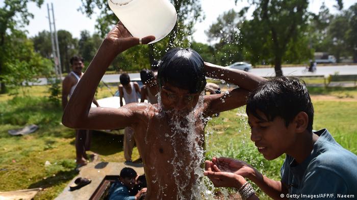 Two boys pour water over themselves. (Photo: FAROOQ NAEEM/AFP/Getty Images)