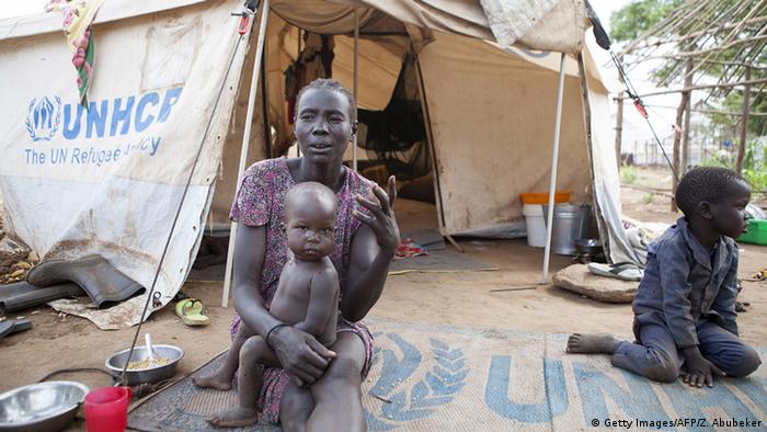 A woman with her child outside a UNHCR tent at a refugee camp