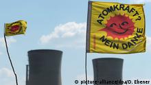 ARCHIV - Atomkraftgegner halten am 25.04.2011 in Bergrheinfeld (Unterfranken) zwei «Atomkraft Nein Danke»-Fahnen vor die Kühltürme des Atomkraftwerks Grafenrheinfeld. Foto: David Ebener/dpa (zu: Bericht: AKW Grafenrheinfeld geht sieben Monate früher vom Netz vom 28.03.2014) +++(c) dpa - Bildfunk+++