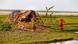 A windswept shack on a patch of grass surrounded by water A windswept shack on a patch of grass surrounded by water