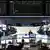 Traders sit at their desks in front of the DAX board at the Frankfurt stock exchange
