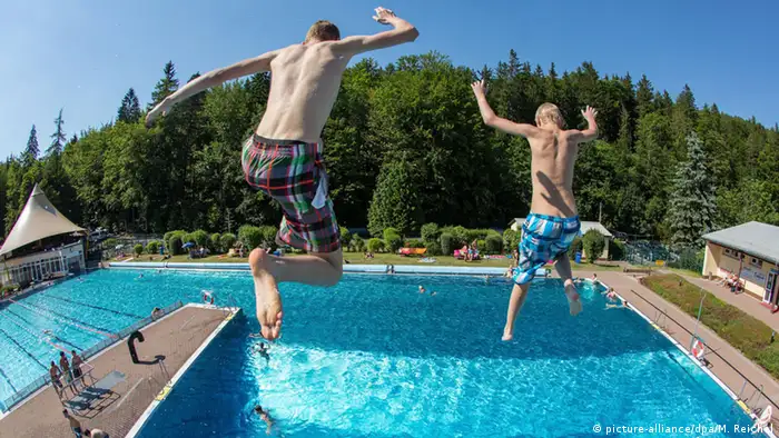 Zwei Jungen springen in einem Freibad ins Wasser. (Foto: dpa)