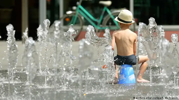 Ein kleiner Junge kühlt sich an einem Springbrunnen ab. (Foto: dpa)