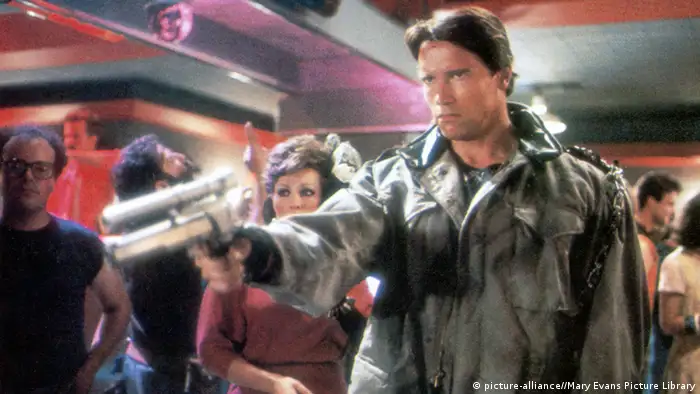 Arnold Schwarzenegger in seiner Rolle als Terminator mit Waffe in der Hand. (picture-alliance//Mary Evans Picture Library)