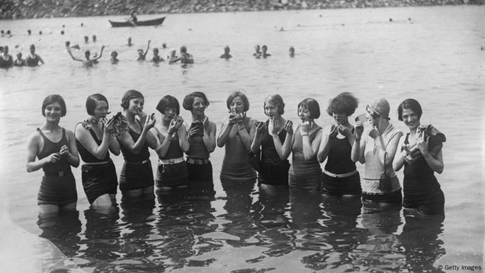 Women with page-boy haircuts and shorter bathing suits standing in the water