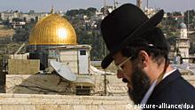 An ultra-Orthodox Jew is seen against the background of the Western Wall, Judaism's holiest site, and the golden Dome of the Rock at the Al-Aqsa mosque compound, Islam's third holiest shrine, in Jerusalem's Old City 26 December 2000, one day before the deadline for Israel and the Palestinians to deliver their verdict on the last-ditch peace plan proposed by outgoing US President Bill Clinton. dpa