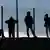 Migrants are seen in silhoutte as they stand on a rise near a fence as they gather near the Channel Tunnel access in Frethun, near Calais, France, July 30, 2015 (Photo: REUTERS/Pascal Rossignol)