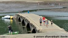 04.08.2015 **** ARCHIV - Touristen gehen am 04.08.2015 Im Edersee bei Asel (Hessen) über eine vierbogige Brücke. Wenn im Sommer der Edersee viel Wasser verliert, zeigt er sein altes, sonst versunkenes Gesicht. Foto: Uwe Zucchi/dpa (zu dpa-Korr: «Das «Edersee-Atlantis» taucht auf» vom 08.08.2015) +++(c) dpa - Bildfunk+++