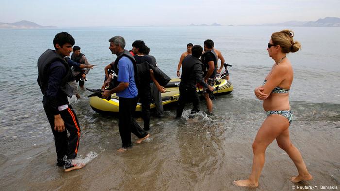 Flüchtlinge kommen an, Touristin läuft vorbei (Foto: REUTERS/Yannis Behrakis)