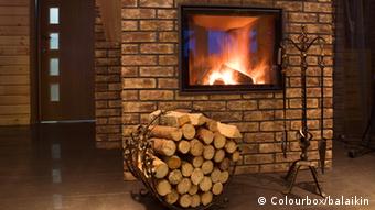 Ein brennender Kamin in einer Wohnung, davor ein Gestell mit Brennholz