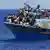 Беженцы прыгают в воду с перегруженного судна у побережья Ливии