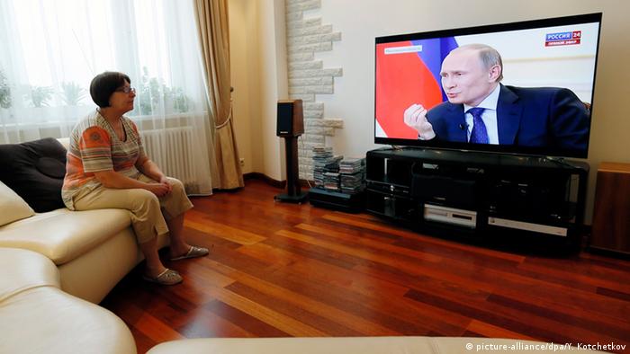Eine Frau schaut sich Putin im Fernsehen an (Foto: dpa)