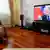Жінка перед телевізором, на якому показують Володимира Путіна на тлі російського прапора (архівне фото)