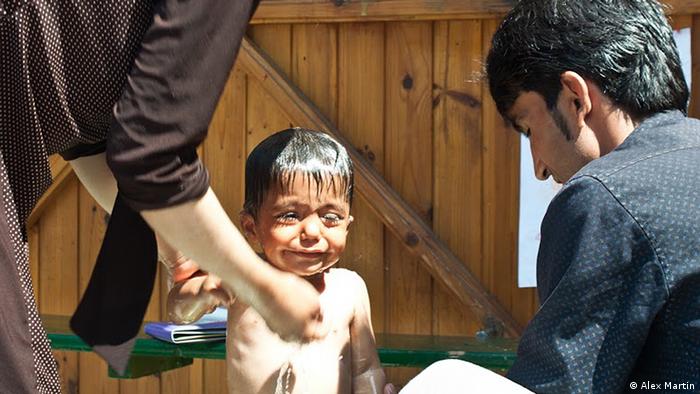 Refugees bathe a child outside of Szeged train station