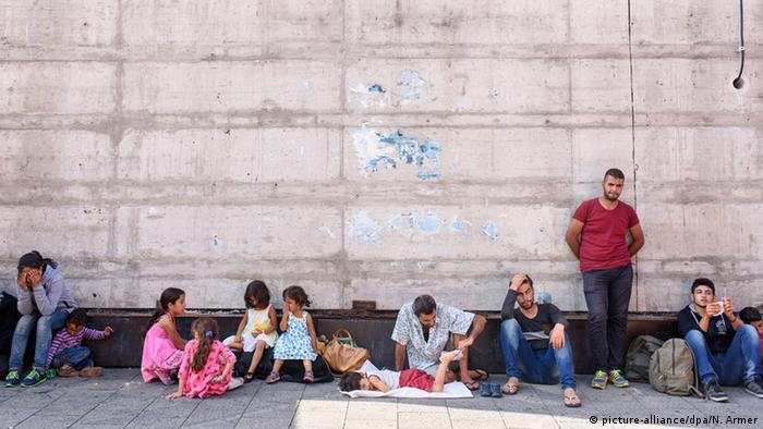 Refugees with their children sitting against a wall. (Photo: Nicolas Armer/dpa)