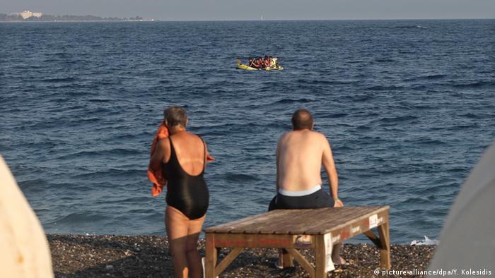 Urlauber der Insel Kos schauen auf ein Boot mit pakistanischen Flüchtlingen (Foto: EPA/YANNIS KOLESIDIS) 