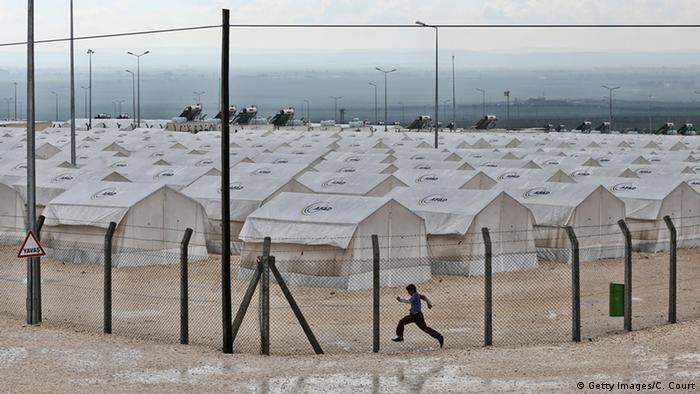 Urlauber der Insel Kos laufen an Zelten von Flüchtlingen vorbei (Foto: Carl Court/Getty Images)