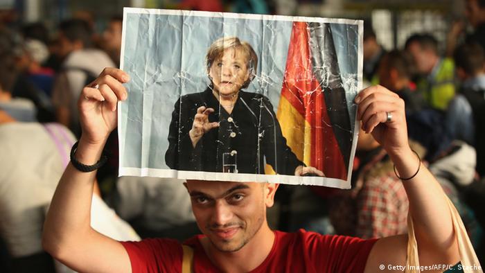 Flüchtlinge mit Merkel Plakaten (Foto: CHRISTOF STACHE/AFP/Getty Images) 