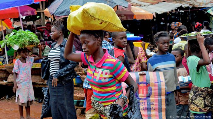 People carry bags and food at a market in Kenema, Sierra Leone