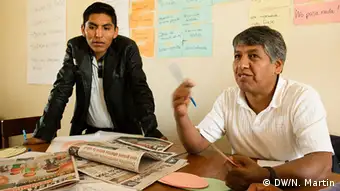Zwei Teilnehmer diskutieren über einen Stapel Zeitungen (Foto: Nicolas Martin).