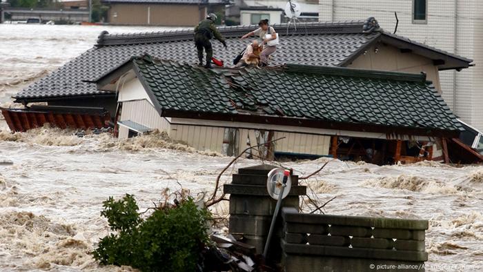 People stand on top of a house underwater in the aftermath of the Japanese tsunami People stand on top of a house underwater in the aftermath of the Japanese tsunami