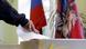 На российском избирательном участке: человек опускает в урну бюллетень для голосования
