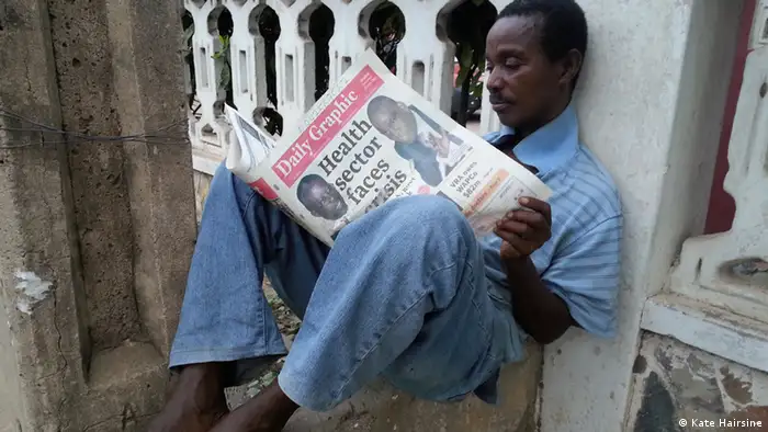 A sitting man reads a newspaper